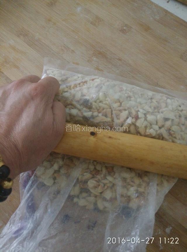 花生晾凉后，把皮搓掉，把花生米装在食品袋中，用擀面杖适当压碎。