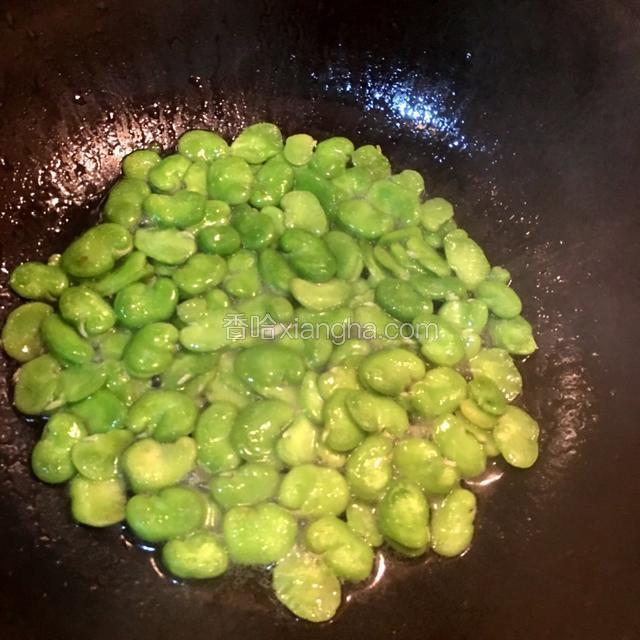 炒至蚕豆颜色变成深绿色时加入适量的盐和清水，炒匀，盖上锅盖焖3分钟。