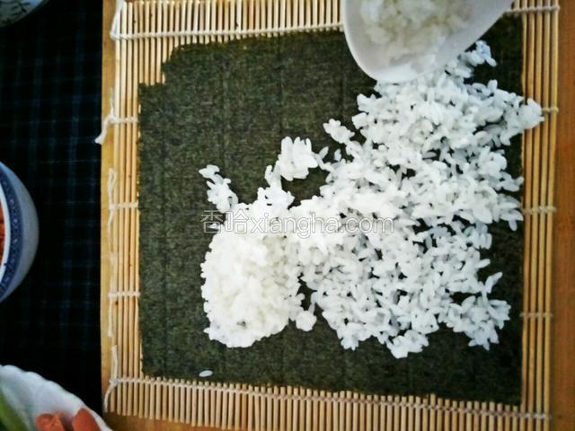 铺好竹帘海苔，米饭涂抹在海苔上，尽量用勺子把米饭压实
