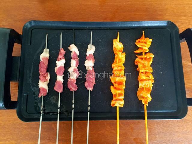 将电烤盘预热，选择中火，涂抹食用油，油热放入羊肉串烤制
