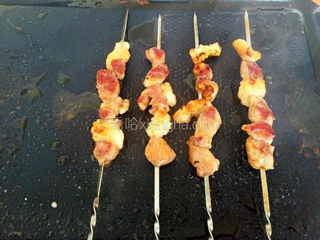 用铲子轻轻按压使羊肉串均匀受热
