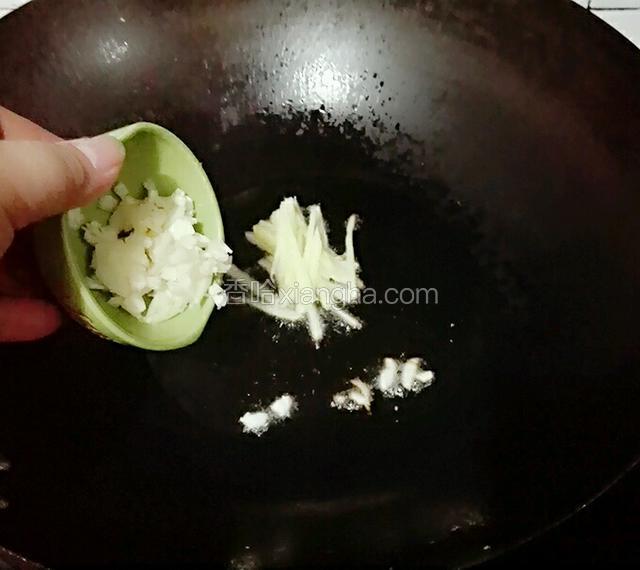 另起锅烧热倒入姜丝和大蒜炒香。