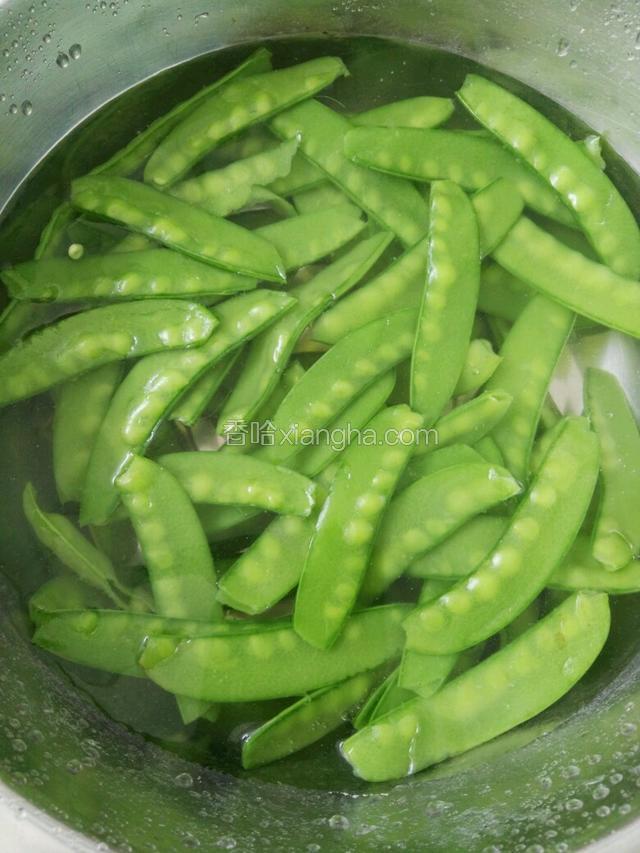 把荷兰豆倒入盆里，用凉水冲后捞出。