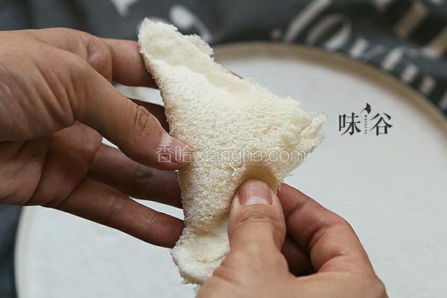 把切去边缘的面包片角对角对折，用手从两边向中间捏起，捏一定要捏紧实了，要不炸的时候雪糕留出来会爆油。

