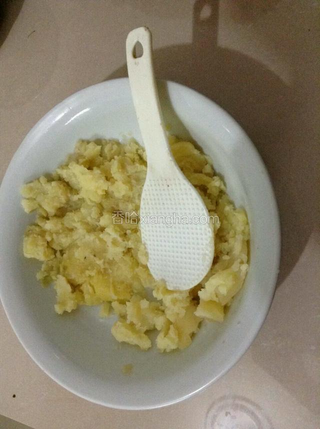 蒸熟的土豆用勺子碾碎。