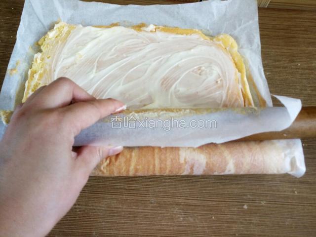 借助擀面丈反向包裹油纸轻轻推动蛋糕向前卷起来。注意别把油纸一起卷进去了。