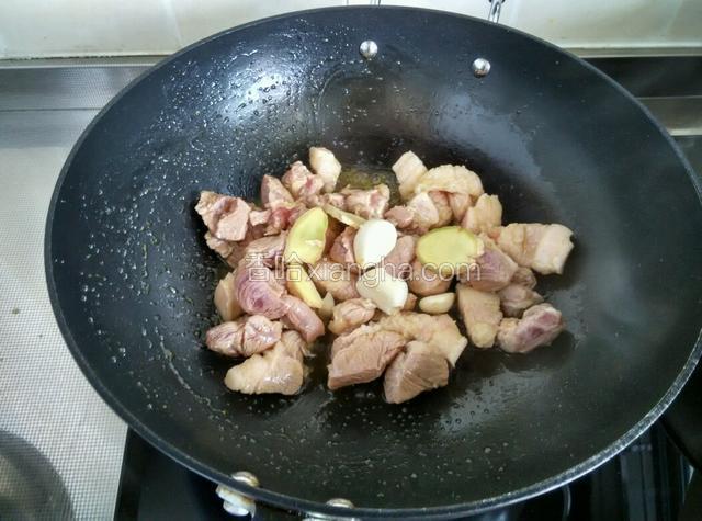 放入肉块翻炒上色，放姜片蒜头炒香