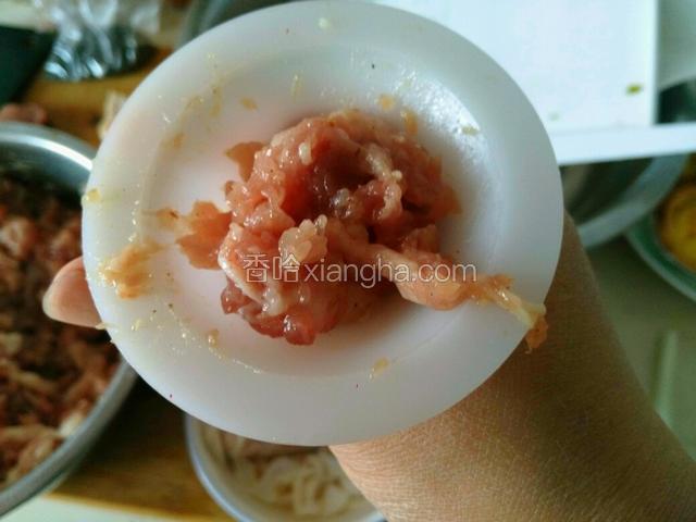 把肉馅顺漏斗灌进肠衣