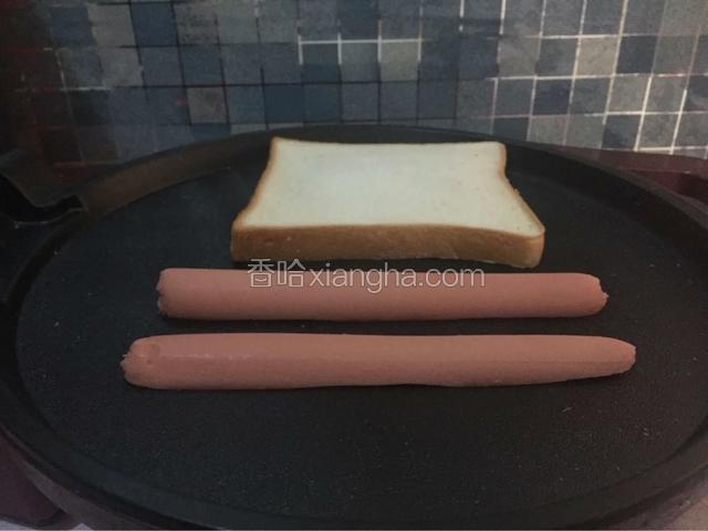 电饼铛预热用纸巾擦干，放入吐司和火腿（火腿肠）加热