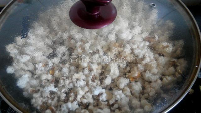 一只手端着锅把，一只手按着锅盖，不时地把锅晃动几下，使玉米均匀受热。记着不要打开锅盖，不然跑的到处都是。