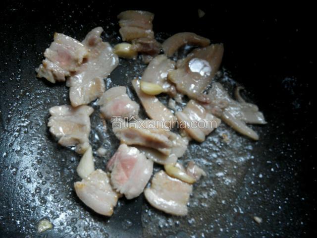 放入腌制好的五花肉，炒至变色。