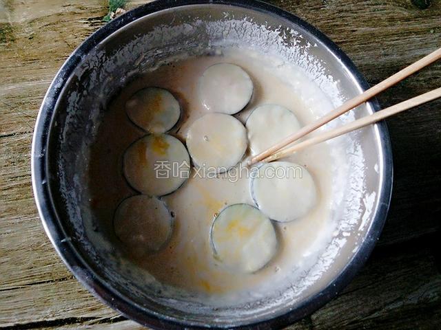 将夹好馅的茄子放入事先调好的面糊糊中，裹上面糊