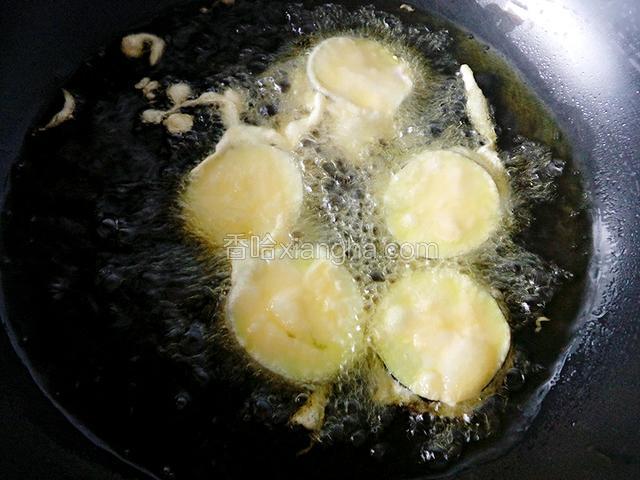 锅中油开后，改为小火，放入裹好面糊的茄子炸制