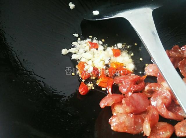 煸岀油后，把腊肠推到边上，放入蒜和红椒爆香