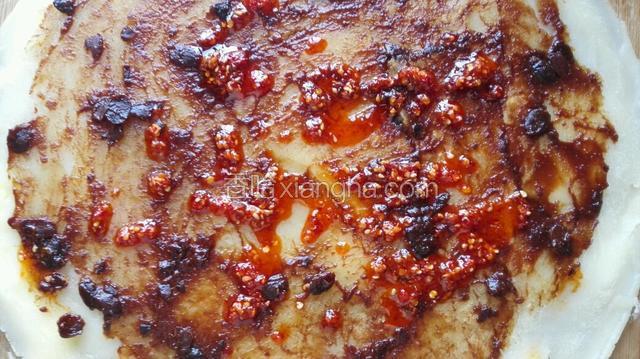 饼烙好后把不带鸡蛋的一面向上，涂抹上豆瓣酱或辣椒酱（根据个人口味）