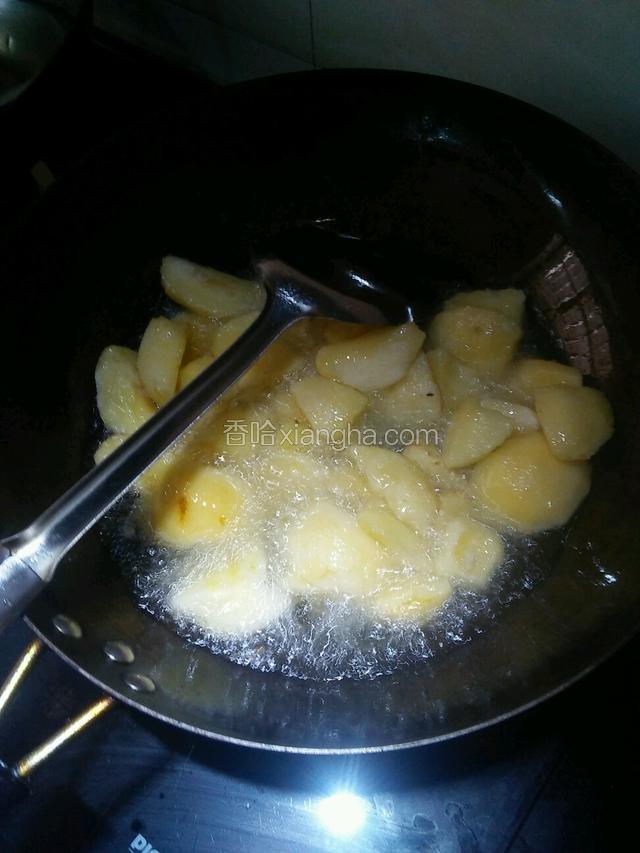 开火锅里倒入油烧五成热倒入苹果炸至金黄