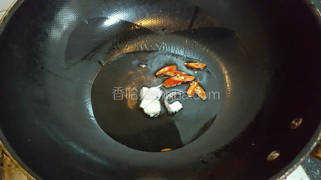 锅内放油八分热后下朝天椒 和蒜炒香。