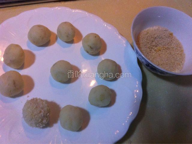 将土豆泥做成自己喜欢的形状--圆饼 椭圆 方块等。我这次搓成圆球，注意要大小差不多，面包糠倒入小碗里，分别将搓好的圆土豆放面包糠里均匀滚一圈