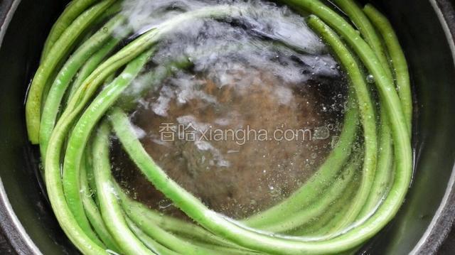 水里加几滴油，水开后整根的豆角放入水中煮熟捞出沥干水