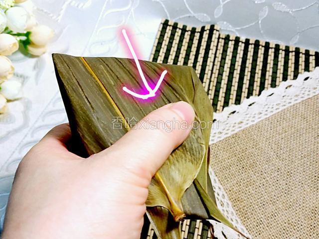 再將前方的粽葉向着粽子方向折過來，折成一個四角的粽子
