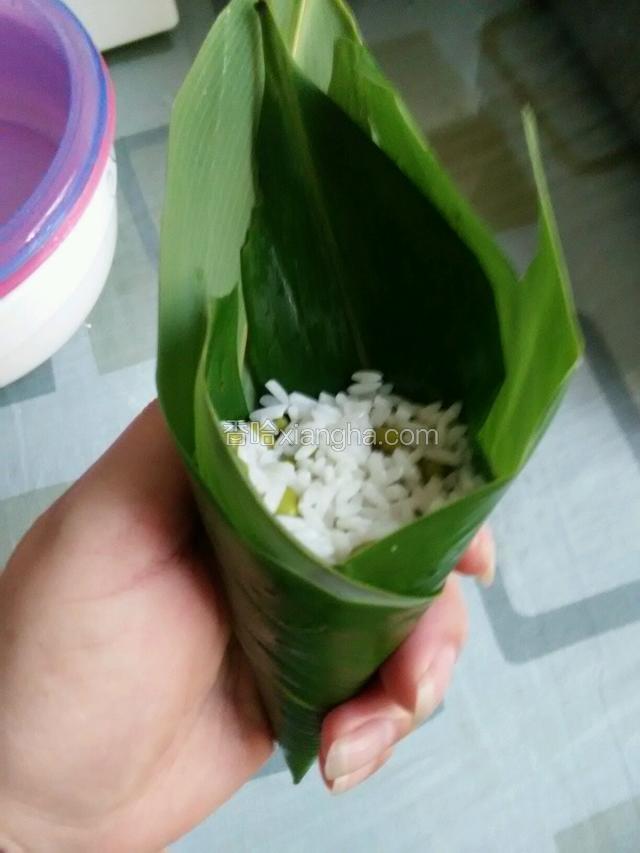 用勺子放入糯米，成筷子插紧，再用大拇指把上面压平