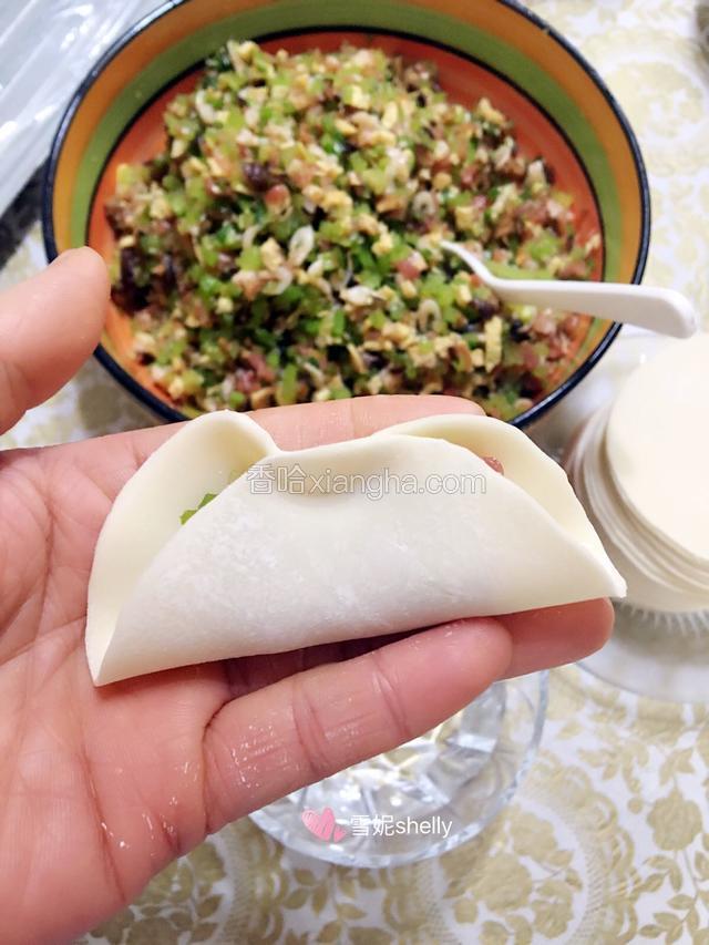 另取一碗放入清水，在饺子皮四周涂上清水后在中间位置对捏一下。
