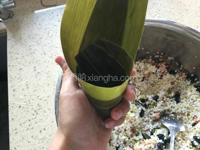 卷成漏斗形状，粽叶根部在下，尖部在上。