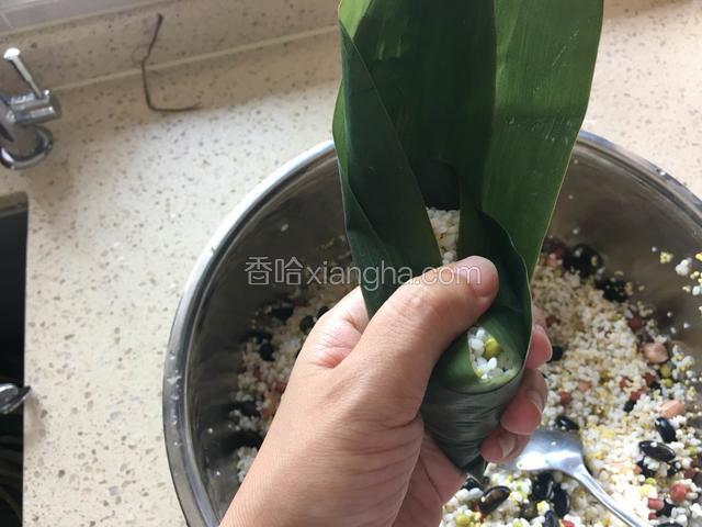 左手大拇指压住粽子左右两侧。