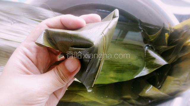 手的虎口捏紧下面，将上面的叶子平折下来，多余的叶子围着粽子缠绕！