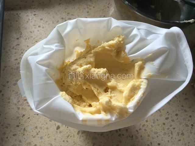 将裱花嘴放入曲奇裱花袋里，然后把裱花袋放进一个宽口杯子里，把曲奇面糊填入裱花袋。