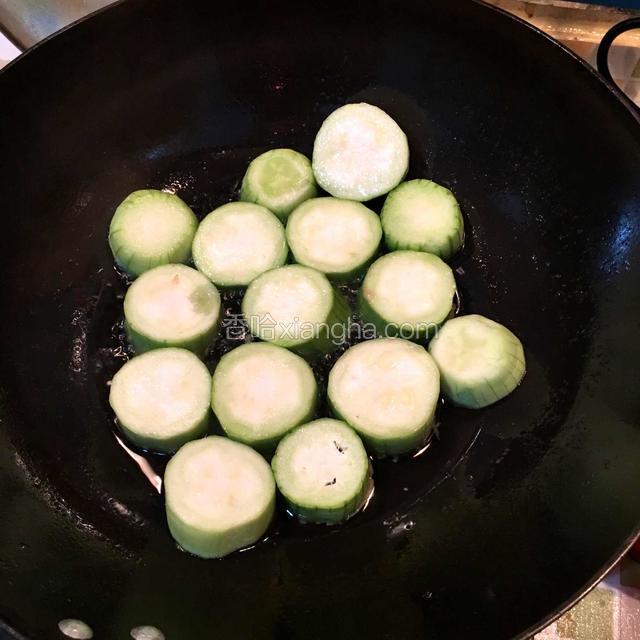 热锅下油，油温七成改小火，将酿好的丝瓜一个个放进锅里煎一下，有肉的一面先煎