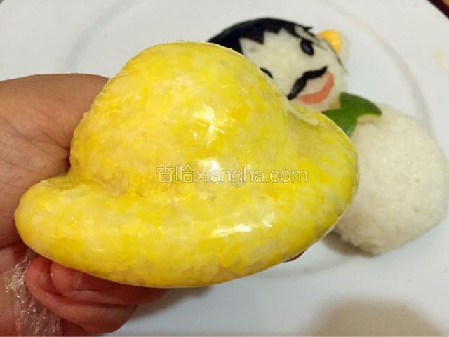蒸好的南瓜和米饭搅拌均匀称为黄色饭团，取一块黄色饭团利用保鲜膜制作出帽子的形状


