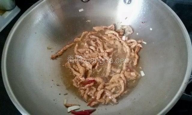 起炒锅放花生油，爆香葱姜干辣椒，放肉丝煸炒。