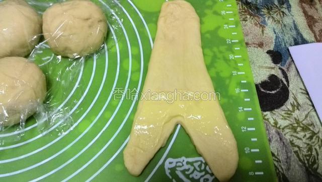 把面团擀成三角形，剪一口子涂上卡仕达酱卷起来