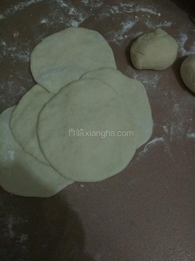 加点干粉再次把面团揉一揉排气，再切成等量面团，用拌面杖擀成边沿薄中间厚的面皮
