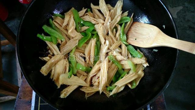 将锅烧热，倒入香油，放入青椒翻炒，然后放入腐竹，继续翻炒。