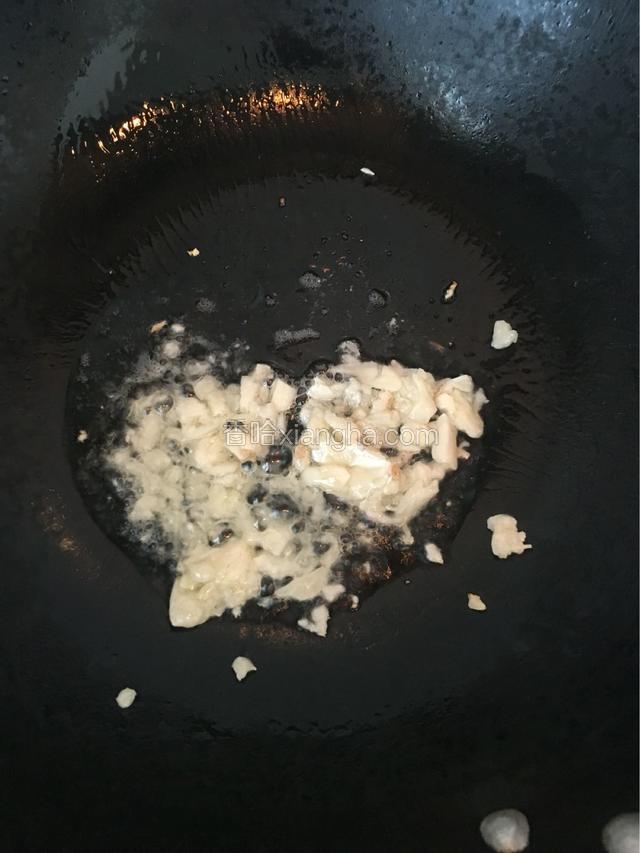 待油温六七成热时下蒜碎，炒出香味