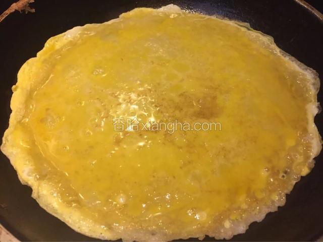 5.将鸡蛋倒入饼上，快速晃动平底锅使其成为一个圆饼
