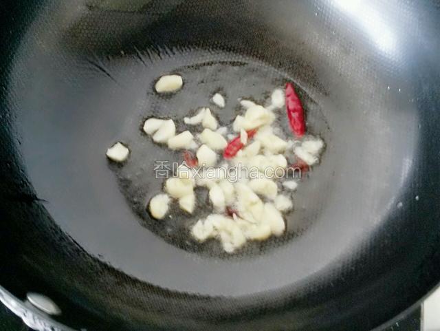 开火坐锅，倒适量油，放两个干红辣椒、两瓣八角和大蒜末，爆炒出香味。