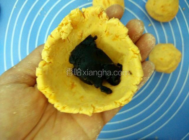 取一份面团包入适量的馅料，像包包子一样包好，搓圆压扁