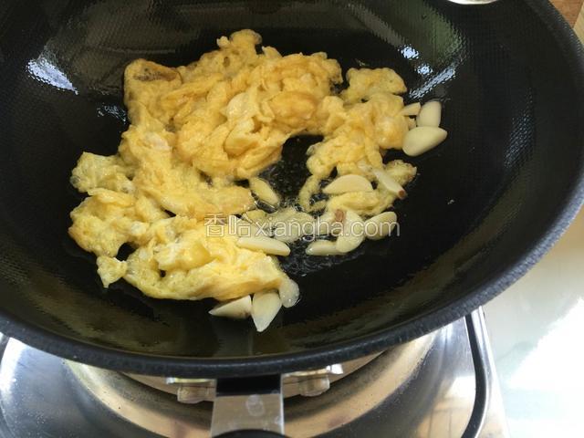 把鸡蛋炒散后加入蒜片炒香。