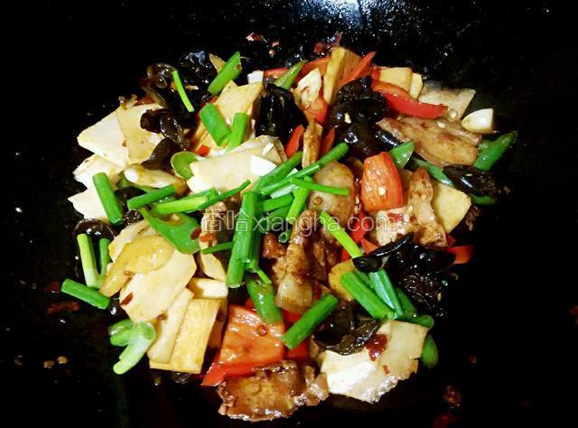 倒入五花肉，加少许酱油上色，撒入葱段。