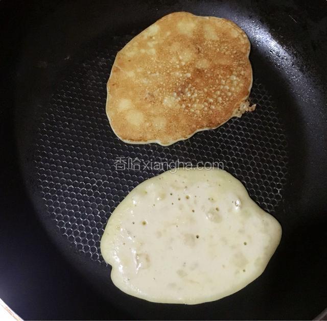 热锅刷上少许油，用勺子舀一勺面糊倒入平底锅内，等面糊表面有很多气孔时翻面煎另一面，依次类推