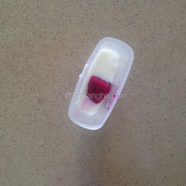 搅拌好的酸奶倒入一半冰盒中，然后再放入两小块火龙果塞满冰盒
