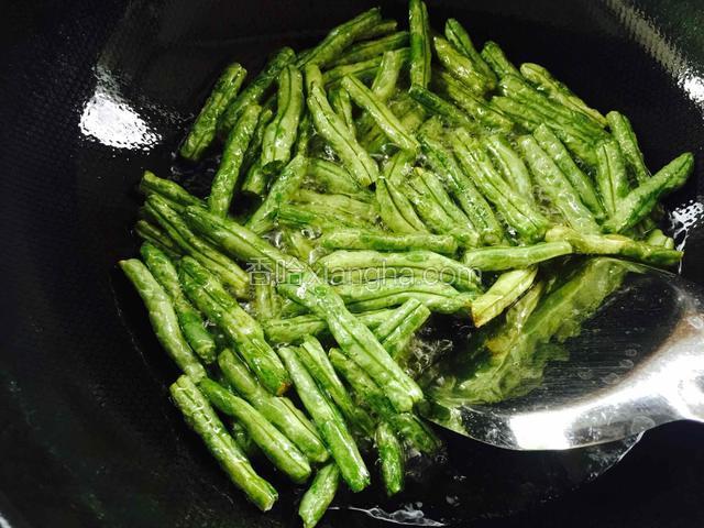 热锅倒入比炒菜多一些的油，放入豆角油炸，使豆角炸到皮变的皱了就可以捞出了。