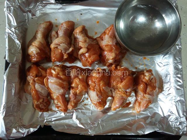 烤箱提前180℃预热10分钟，鸡腿放入烤盘码齐，放入一碗水。腌制鸡腿的调料水留着备用。