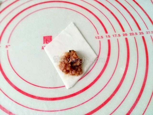 用筷子夹起肉馅放面皮的一角，开始卷，