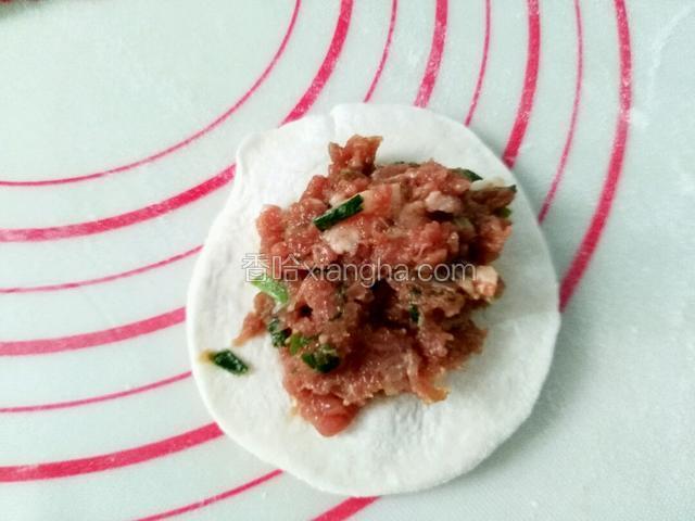 拿起一个面皮，中间放上肉馅，