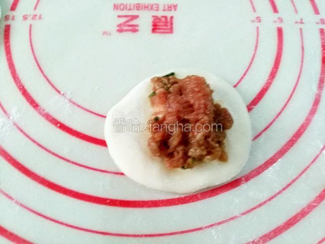 取一个面皮放上肉馅，从一头开始捏褶，