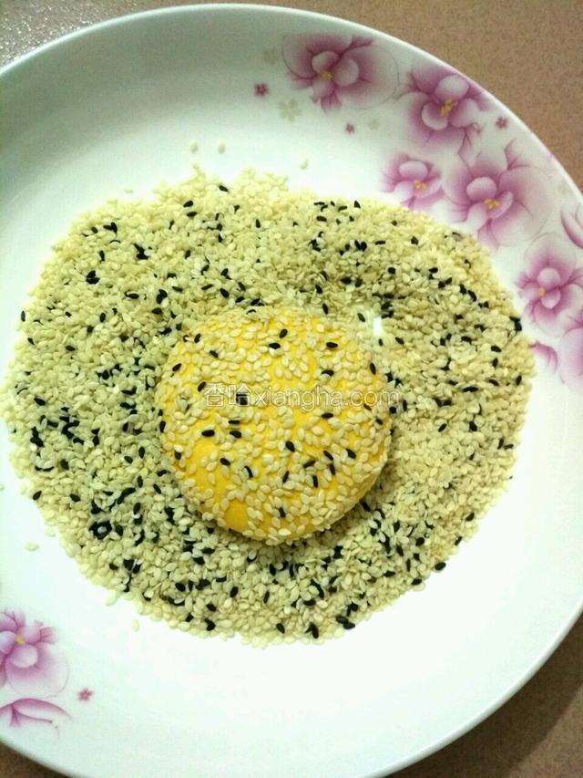 再用手掌按扁放到芝麻里面使外边都粘上芝麻